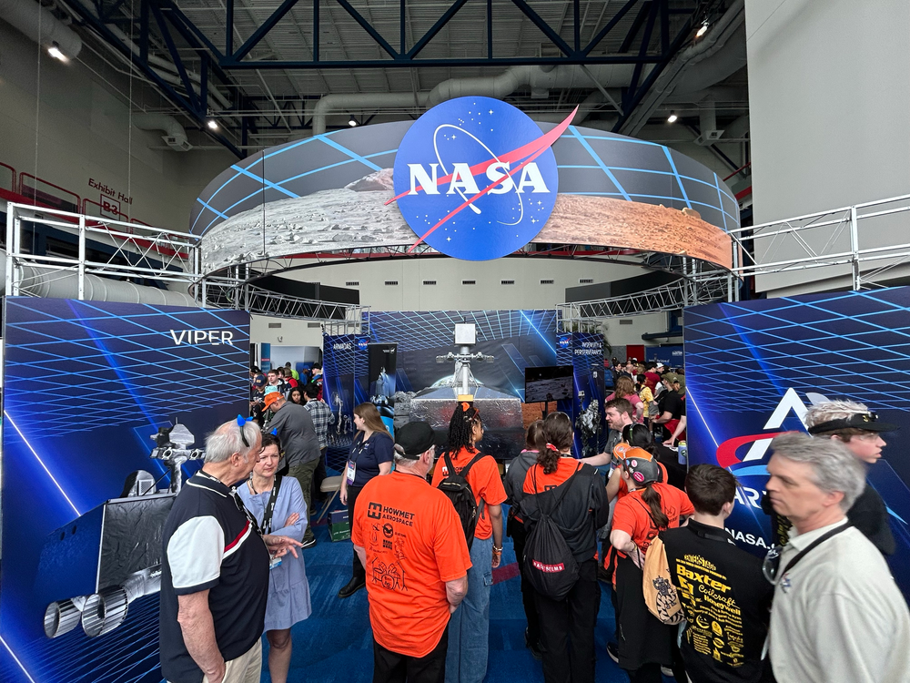 A group of people in a large facility explore an exhibit. 